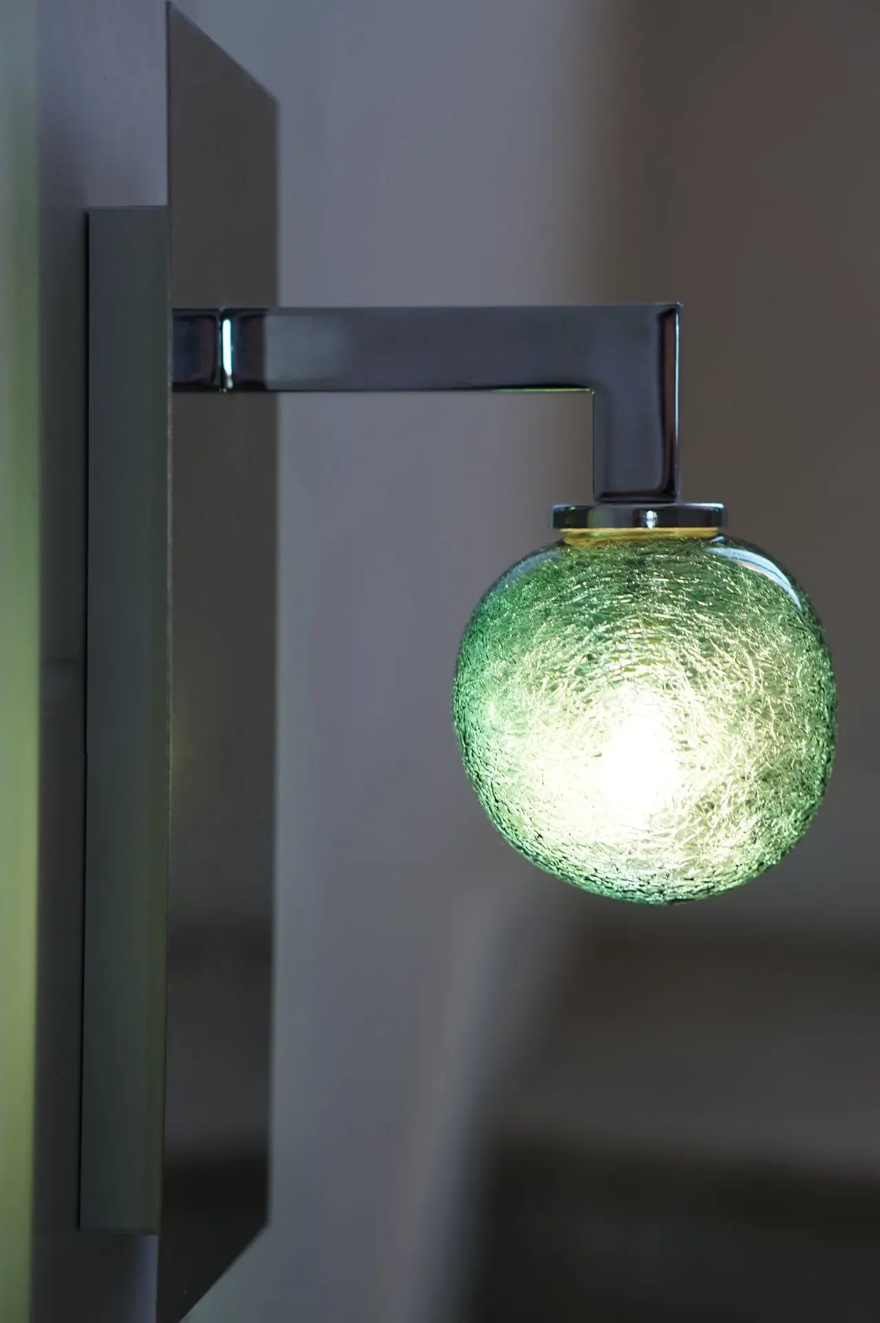 luminaire simple accroché à un mur par un crochet. Verre restistant a l'humidité de couleur verte avec des fils argenté à l'interieur de forme ronde